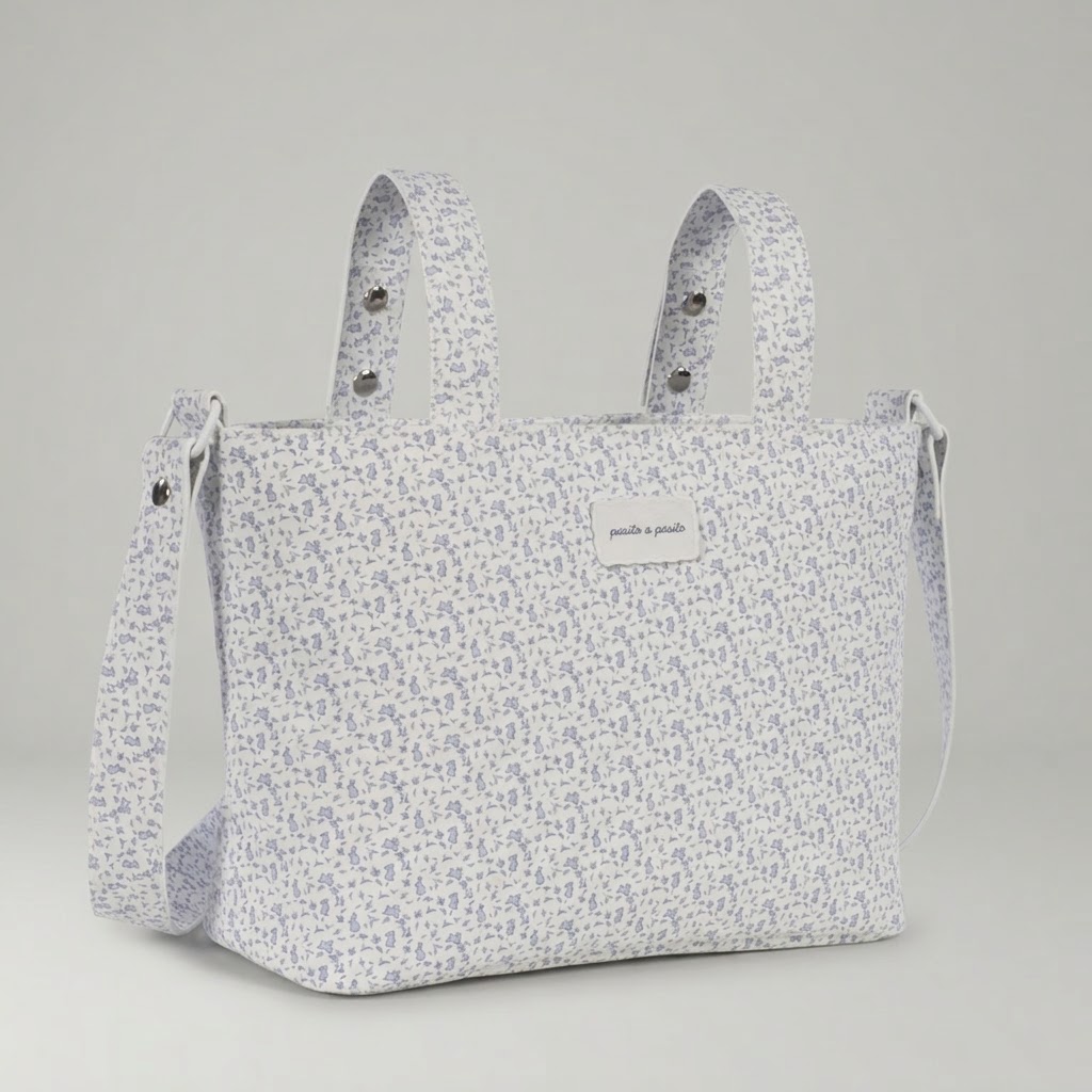 Bolso Crossbody Maison Tender Flores Azules Conejitos Piel- Pasito a Pasito Bolso Crossbody Maison Tender Flores Azules Piel de la reconocida firma de puericultura Pasito a Pasito combina la elegancia atemporal con la funcionalidad que toda familia necesita. Diseñada para facilitar el día a día, este bolso se convierte en un accesorio imprescindible tanto para preparar la llegada del bebé en el hospital como para disfrutar de los paseos diarios. Diseño floral y estilo inconfundible El modelo bolso crossbody Maison Tender Flores destaca por su delicado estampado, aportando un toque romántico y sofisticado al carrito de tu bebé. Pasito a Pasito es especialista en crear colecciones que no renuncian a la estética, permitiendo a las familias llevar un bolso maternal que complementa perfectamente su estilo personal. Es una pieza que se adapta a diferentes modelos de cochecitos, aportando luz y un diseño cuidado al detalle. Organización y practicidad en cada salida Salir de casa con un bebé requiere llevar múltiples accesorios: pañales, muselinas, biberones y ropa de cambio. Una mochila ofrece la amplitud necesaria para mantener todo ordenado y accesible. Gracias a su estructura, podrás encontrar rápidamente cualquier artículo en momentos de urgencia. Ya sea para una visita al pediatra, una tarde en el parque o una escapada de fin de semana, este bolso te ofrece la tranquilidad de llevar el universo de tu bebé siempre contigo. Bolso crossbody maternal Maison Tender de piel con estampado de flores azules de la marca Pasito a Pasito, ideal para el hospital y paseos diarios.